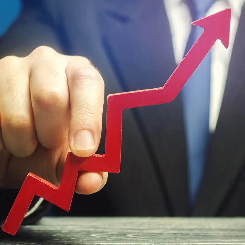 Persona en traje sosteniendo una flecha roja en ascenso, simbolizando crecimiento financiero o aumento del IPC.