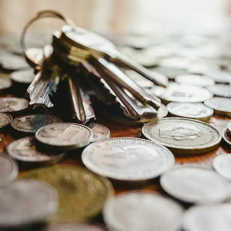 Llaves de casa colocadas sobre monedas, simbolizando propiedades y finanzas.