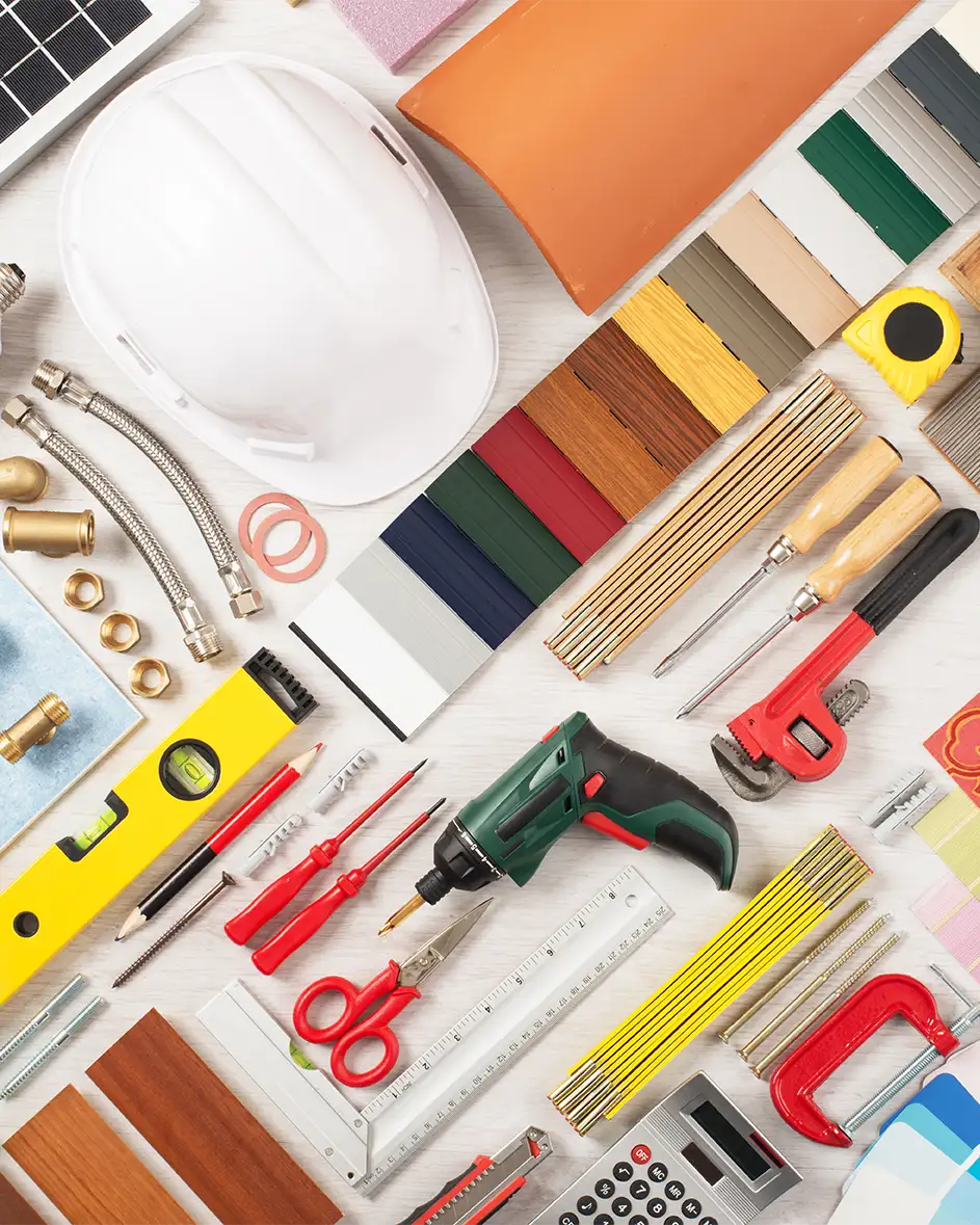 Conjunto de herramientas para reformas y construcción, incluyendo casco de seguridad, destornilladores y taladro.