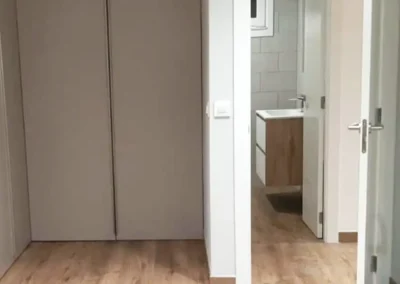 Vista de dormitorio tras la reforma con armario empotrado y acceso al baño.